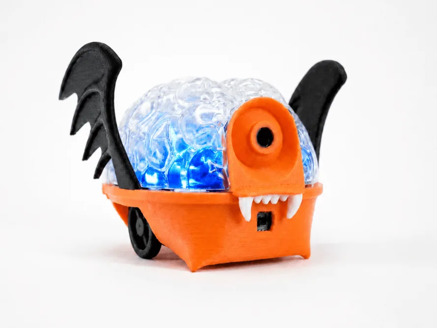 An orange SpikerBot dressed up with black bat wings and fangs.